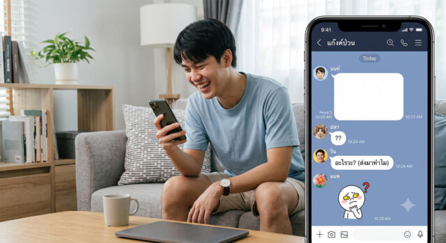 ผู้ชายหัวเราะกับแอปแชทกลุ่มบนสมาร์ทโฟนที่ส่งข้อความเปล่า ภาพ split-screen: ทางด้านซ้าย ผู้ชายชาวเอเชียอายุน้อยนั่งอยู่บนโซฟาสีเทาในห้องนั่งเล่นที่สว่างไสว กำลังยิ้มและหัวเราะขณะมองลงมาที่สมาร์ทโฟนในมือของเขา ทางด้านขวา มีส่วนแทรกหน้าจอสมาร์ทโฟนขนาดใหญ่
